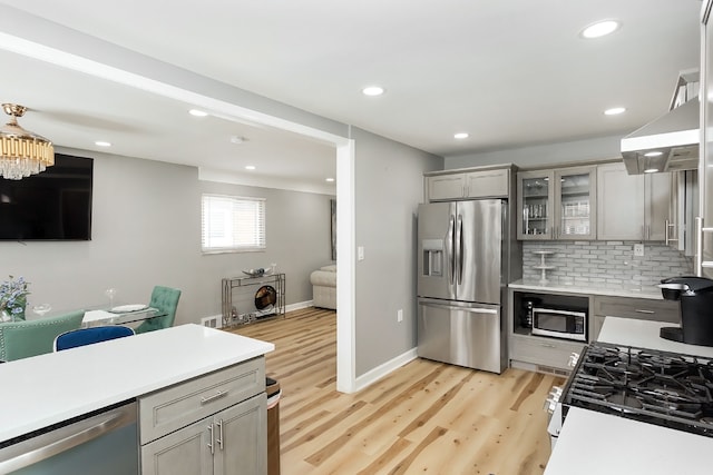 kitchen featuring decorative backsplash, stainless steel appliances, gray cabinets, and light hardwood / wood-style floors