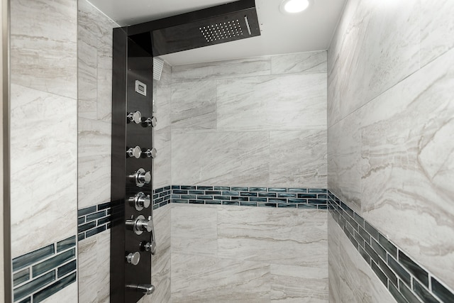 bathroom with a tile shower and tile walls