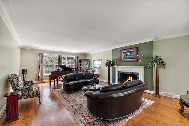 living room featuring a high end fireplace, wood-type flooring, and crown molding