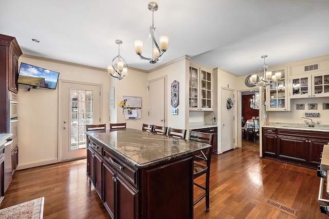 kitchen with dark hardwood / wood-style flooring, a kitchen island, a chandelier, and decorative light fixtures