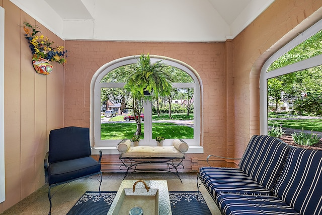 living area featuring vaulted ceiling and brick wall