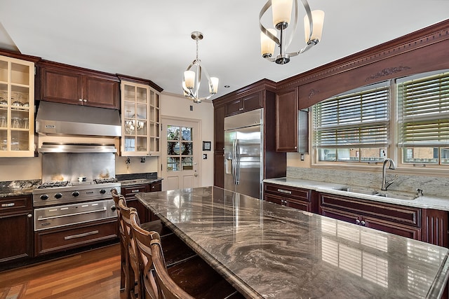 kitchen featuring appliances with stainless steel finishes, dark hardwood / wood-style flooring, sink, decorative light fixtures, and dark stone countertops