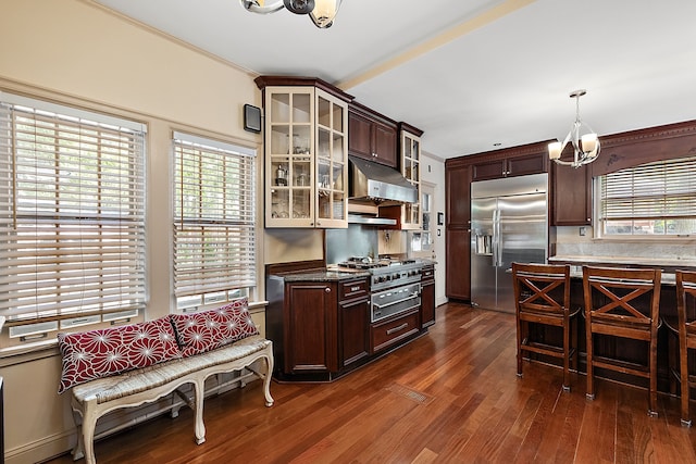 kitchen featuring appliances with stainless steel finishes, dark brown cabinets, dark wood-type flooring, a notable chandelier, and hanging light fixtures