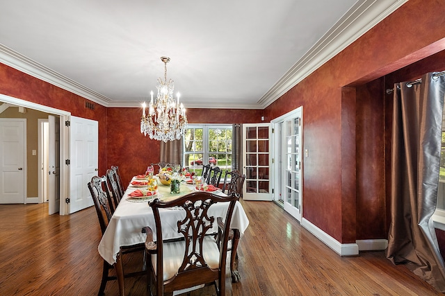 dining space with hardwood / wood-style flooring, ornamental molding, french doors, and a chandelier