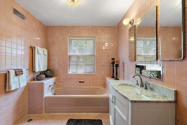 bathroom with vanity, tile patterned floors, tile walls, and a tub