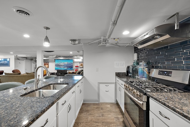 kitchen featuring gas stove, white cabinetry, sink, light hardwood / wood-style flooring, and dark stone counters