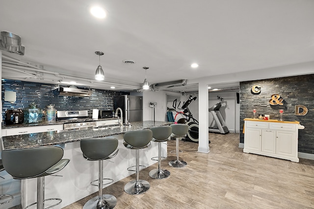 kitchen featuring white cabinetry, hanging light fixtures, stainless steel appliances, and light wood-type flooring