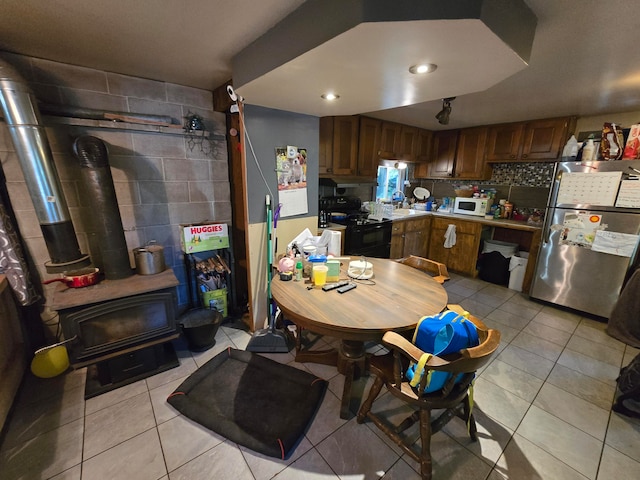 kitchen with tasteful backsplash, stainless steel refrigerator, light tile patterned floors, and black / electric stove