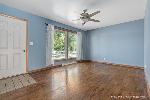 empty room with dark hardwood / wood-style flooring, ceiling fan, and a baseboard heating unit