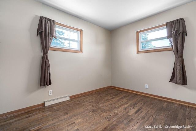 spare room featuring baseboard heating, plenty of natural light, and dark wood-type flooring