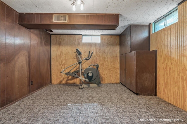 workout area with light carpet, plenty of natural light, and wooden walls