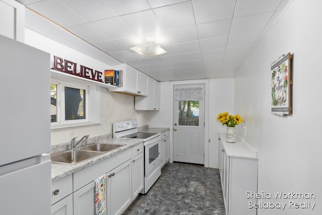 kitchen featuring a drop ceiling, white appliances, a sink, white cabinetry, and light countertops