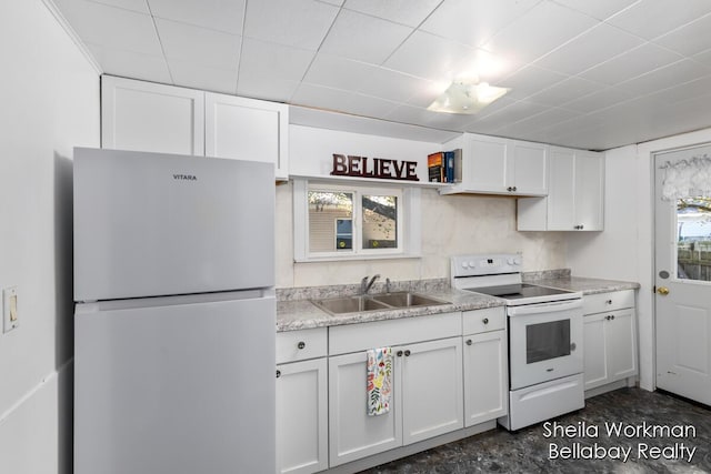 kitchen with white electric stove, white cabinets, freestanding refrigerator, a sink, and a wealth of natural light