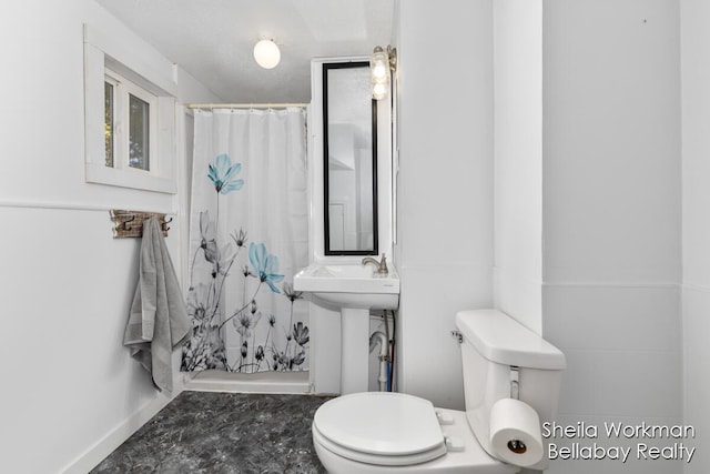 bathroom featuring toilet, a sink, and a shower with shower curtain