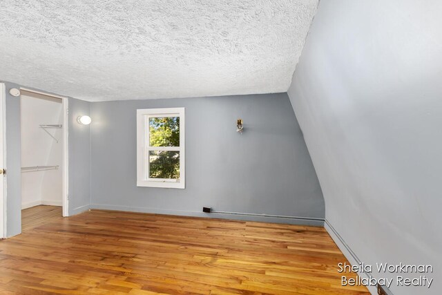 spare room featuring a textured ceiling, baseboards, and wood finished floors