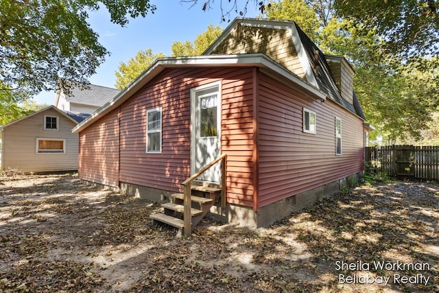 view of property exterior featuring entry steps and fence