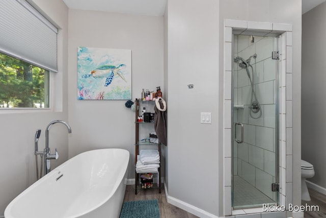 8981 Spruce Ave Unit B, Newaygo, MI 49337 - full bath with wood finished floors, a shower stall, toilet, a freestanding tub, and baseboards