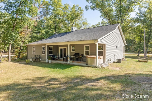 8981 Spruce Ave Unit B, Newaygo, MI 49337 - back of property featuring a lawn, a hot tub, a chimney, a patio area, and central AC