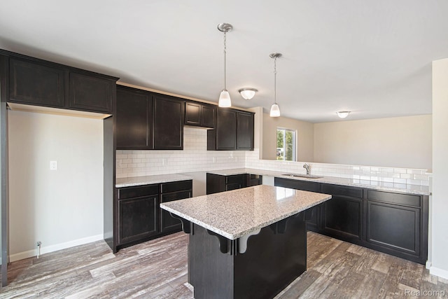4442 Sprauge Ln, Swartz Creek, MI 48473 - kitchen featuring a sink, tasteful backsplash, light stone counters, light wood finished floors, and a kitchen breakfast bar
