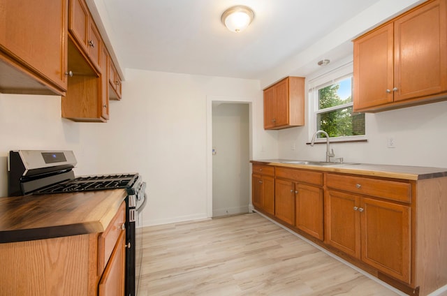 kitchen with stainless steel range with gas cooktop, sink, and light hardwood / wood-style floors