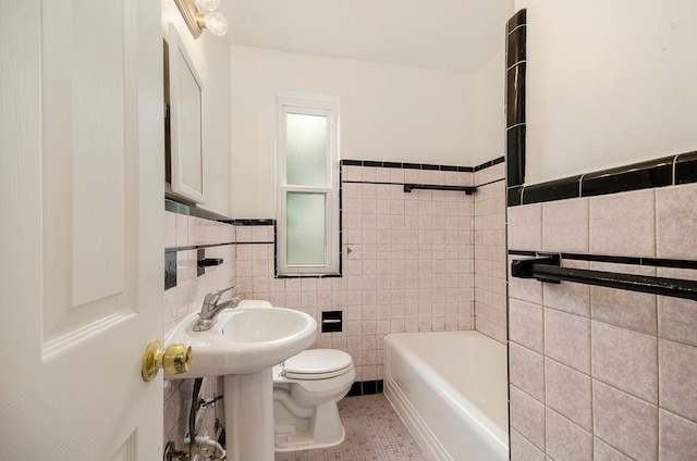 bathroom with tile patterned floors, a tub to relax in, toilet, and tile walls