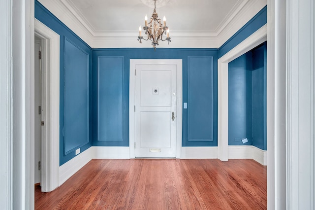 entryway featuring hardwood / wood-style floors, ornamental molding, and a notable chandelier