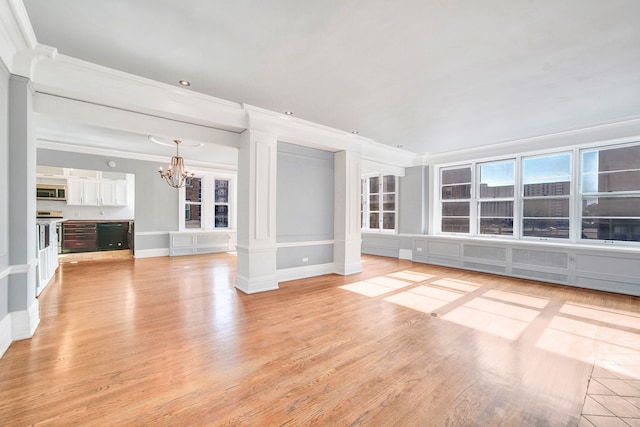 unfurnished living room featuring a notable chandelier, light hardwood / wood-style floors, ornate columns, and crown molding