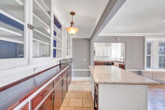 kitchen featuring light stone counters, sink, white cabinets, a center island, and hanging light fixtures