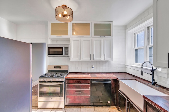 kitchen featuring white cabinetry, sink, stainless steel appliances, wood counters, and backsplash