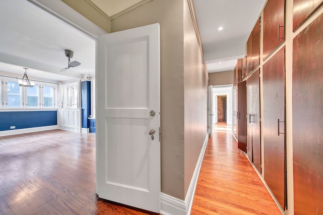 hall featuring a notable chandelier, light wood-type flooring, and ornamental molding