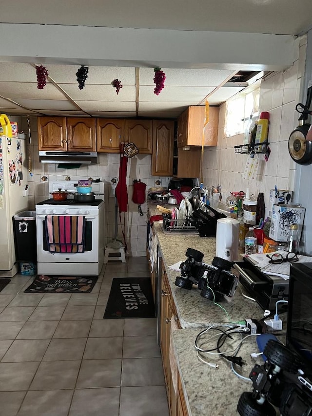 kitchen with tile patterned flooring, light stone countertops, and white appliances