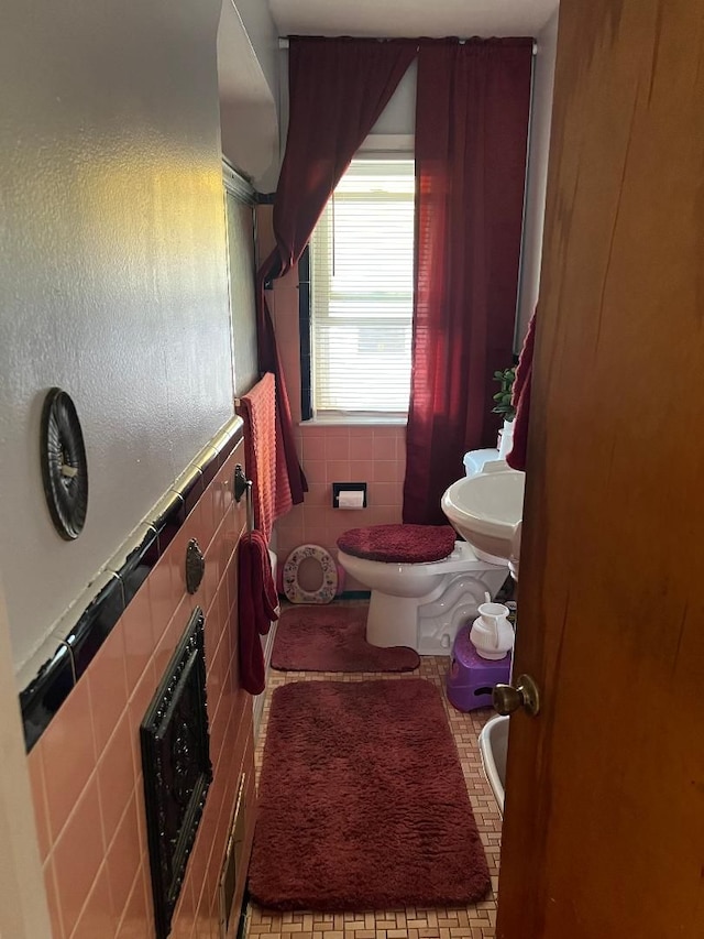 bathroom featuring sink, tile patterned flooring, tile walls, and toilet