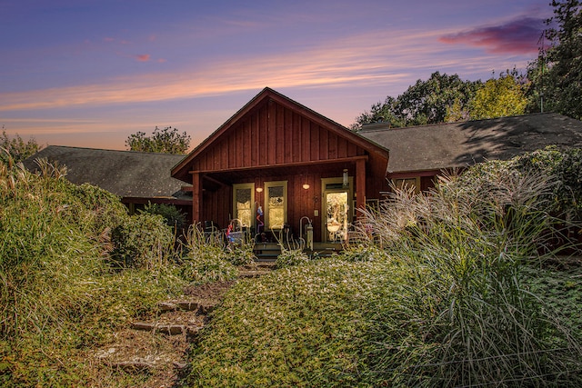 back house at dusk featuring a porch