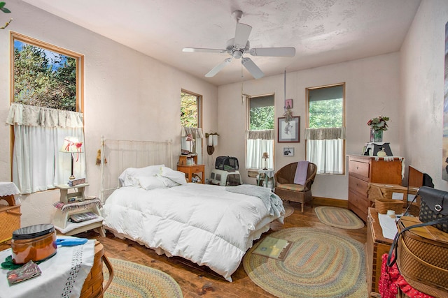 bedroom with ceiling fan, dark hardwood / wood-style floors, and multiple windows