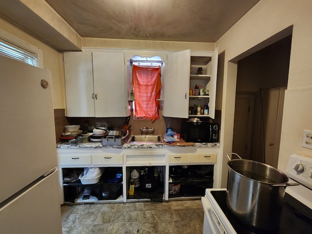 kitchen featuring sink, stainless steel range oven, backsplash, white fridge, and white cabinets