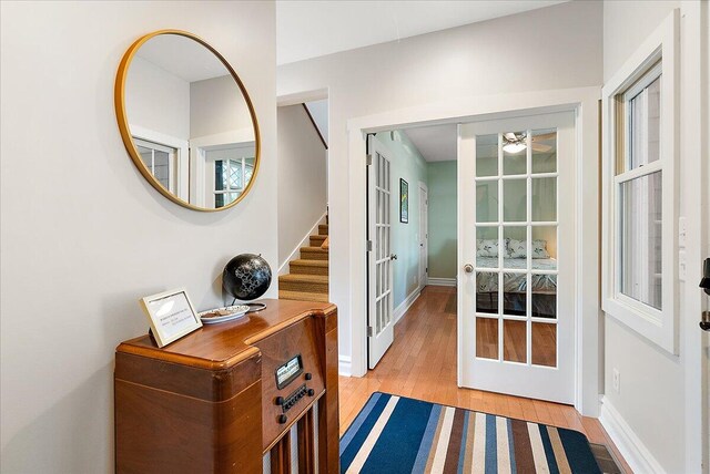 doorway with light wood finished floors, stairway, baseboards, and french doors