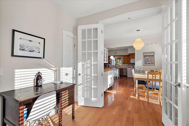 office with french doors and light wood-style floors