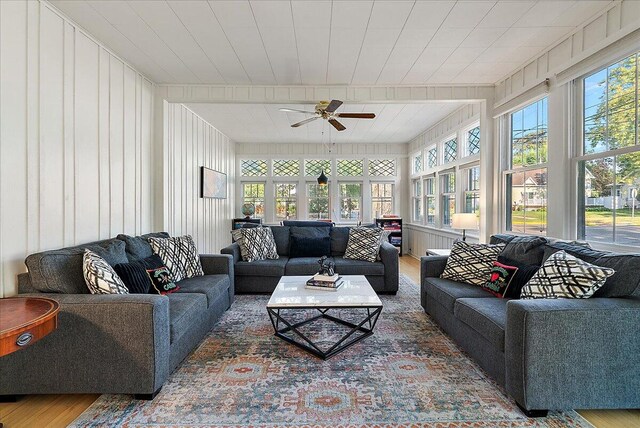 living area with ceiling fan, plenty of natural light, and wood finished floors