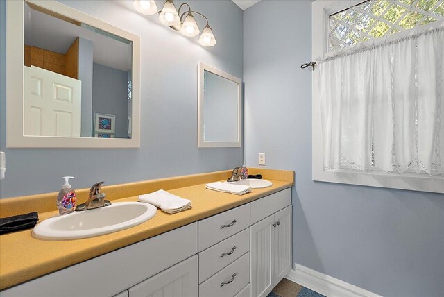 full bath featuring a sink, baseboards, and double vanity