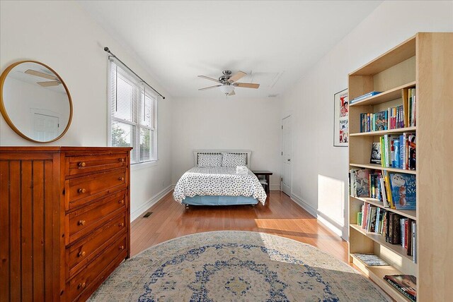 bedroom with light wood-type flooring, visible vents, ceiling fan, and baseboards