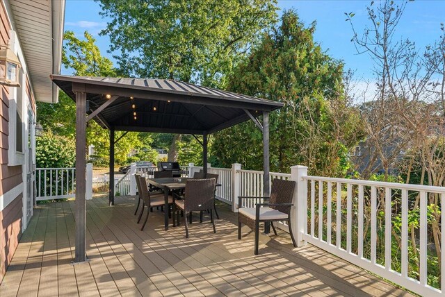 wooden terrace with a gazebo, outdoor dining space, and a grill