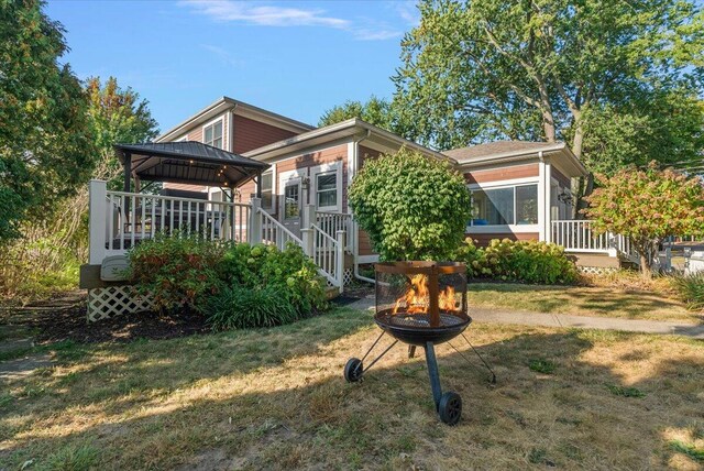 back of property featuring a yard, a gazebo, an outdoor fire pit, and a wooden deck