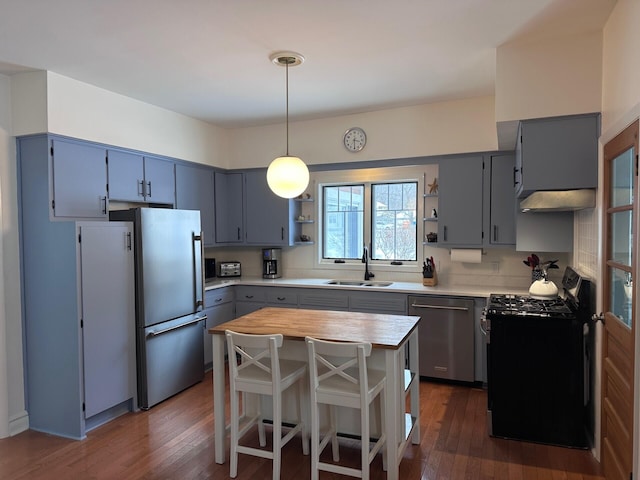 kitchen with a kitchen island, decorative light fixtures, stainless steel appliances, open shelves, and a sink