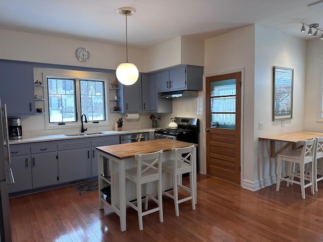 kitchen featuring hanging light fixtures, open shelves, a sink, and a kitchen breakfast bar