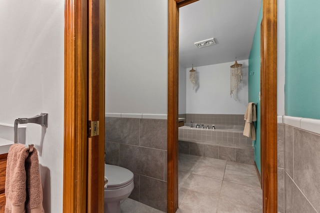 bathroom with toilet, tile patterned floors, tile walls, and a bathing tub