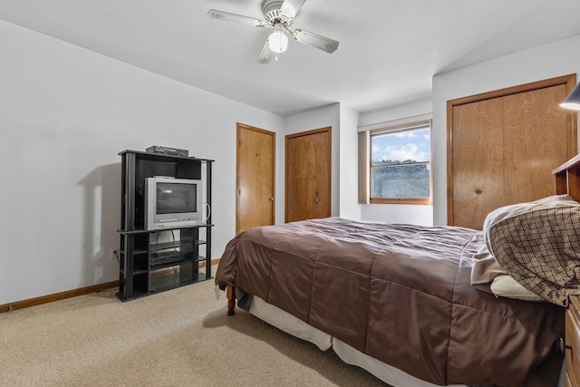 carpeted bedroom with ceiling fan and two closets