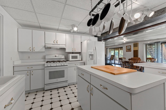 kitchen featuring white cabinetry, a drop ceiling, a kitchen island, and white appliances