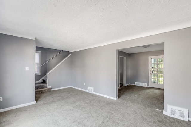 unfurnished living room with carpet floors and a textured ceiling