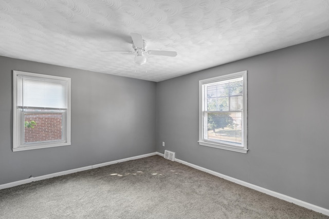 carpeted spare room with ceiling fan and a textured ceiling