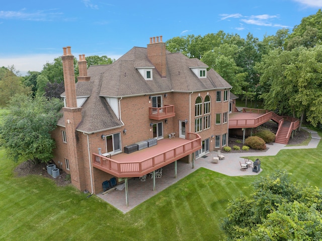 back of house with a wooden deck, a yard, and an outdoor fire pit